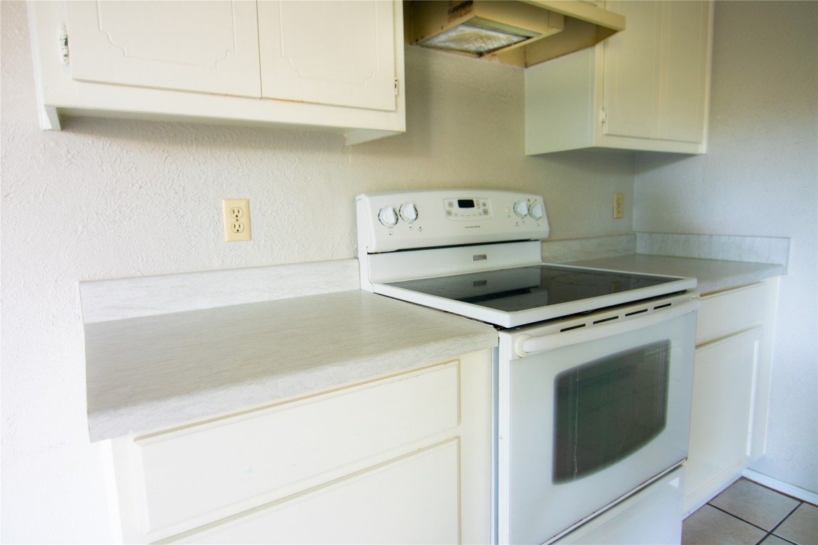8807 Springmail Circle, Unit A Austin, TX 78729 - Photo 24 of 27 a kitchen with granite countertop white cabinets and white stove