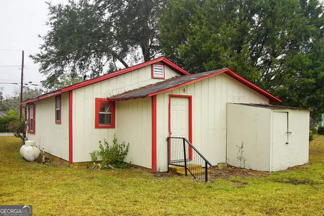 a backyard of a house with plants and large tree