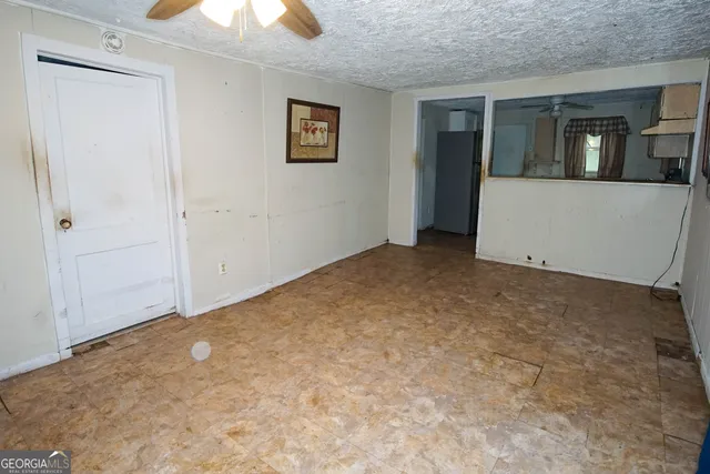 an empty room with a ceiling fan and window