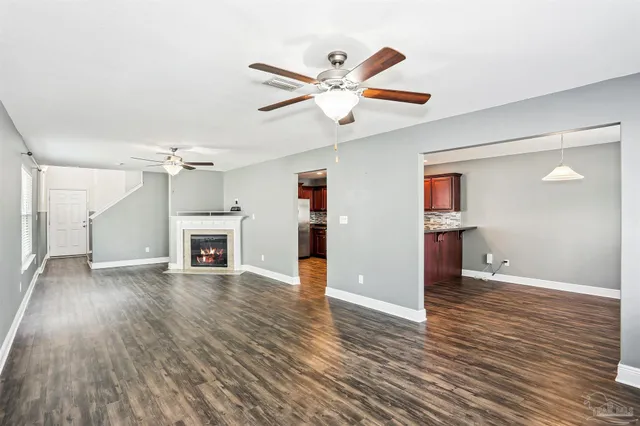 an empty room with wooden floor a ceiling fan and windows