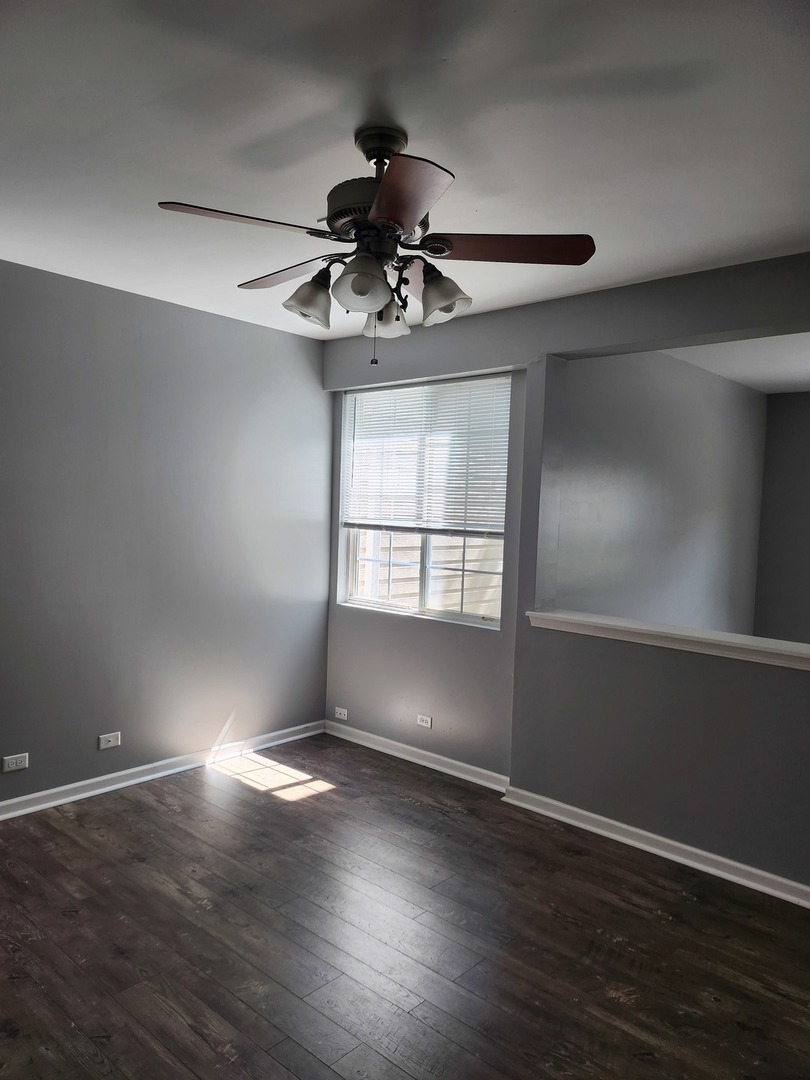 316 East Victoria Circle, Unit 316 North Aurora, IL 60542 - Photo 12 of 54 an empty room with wooden floor chandelier fan and windows