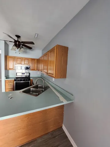 a kitchen with stainless steel appliances granite countertop a sink a refrigerator and wooden floor