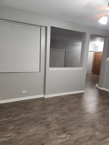 an empty room with wooden floor chandelier fan and windows