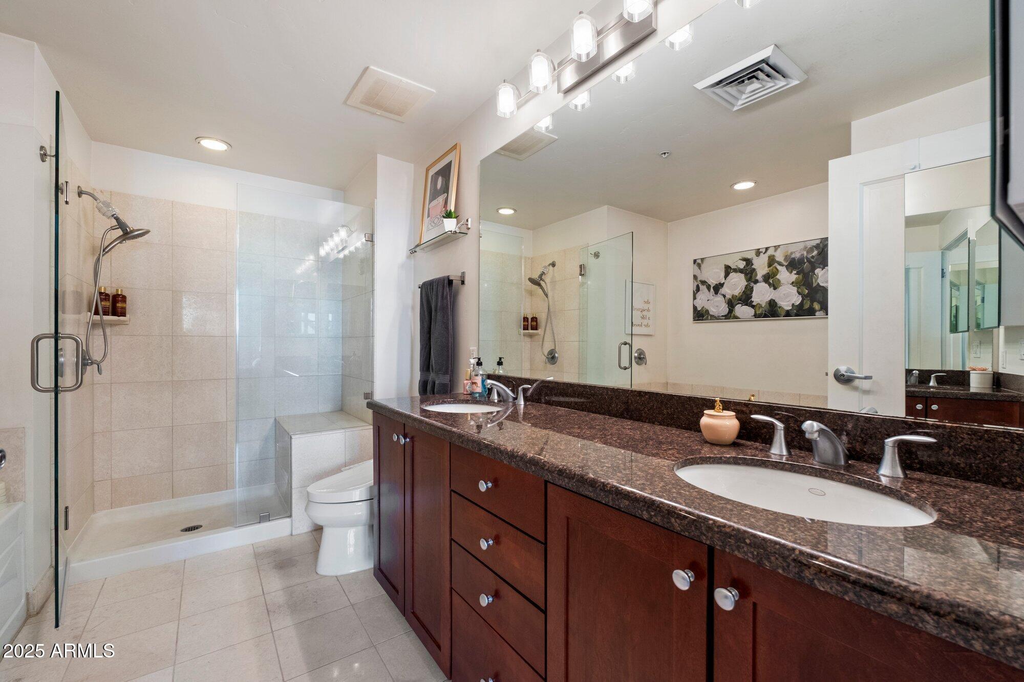 310 South 4th Street, Unit 908 Phoenix, AZ 85004 - Photo 22 of 44 a bathroom with a granite countertop double vanity sink a toilet a mirror and shower