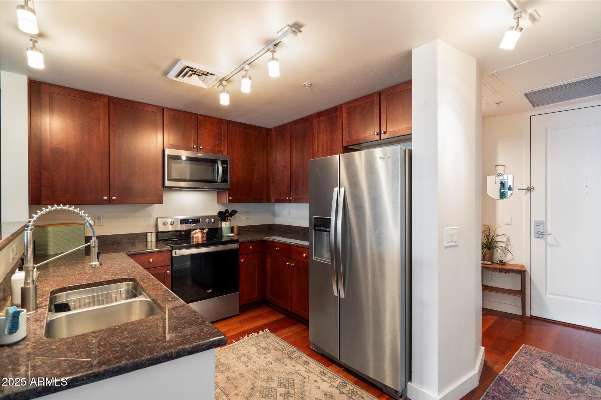 310 South 4th Street, Unit 908 Phoenix, AZ 85004 - Photo 4 of 44 a kitchen with kitchen island granite countertop stainless steel appliances cabinets a sink and a counter top space