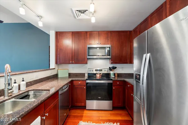 a kitchen with kitchen island granite countertop stainless steel appliances cabinets a sink and a counter top space