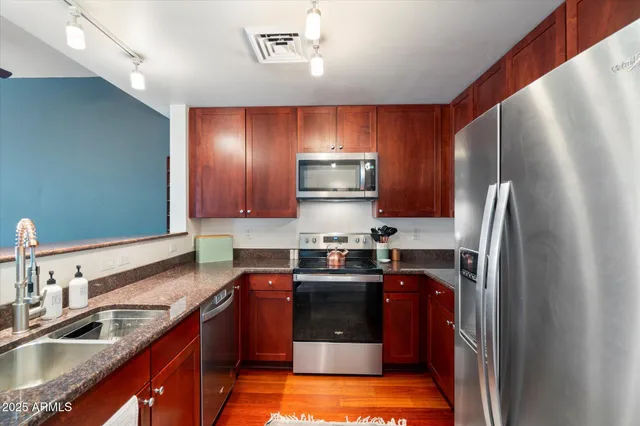 a kitchen with kitchen island granite countertop stainless steel appliances cabinets a sink and a counter top space