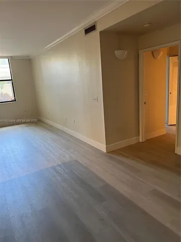 an empty room with wooden floor and windows with curtains