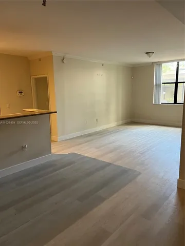 a view of an empty room with window and wooden floor