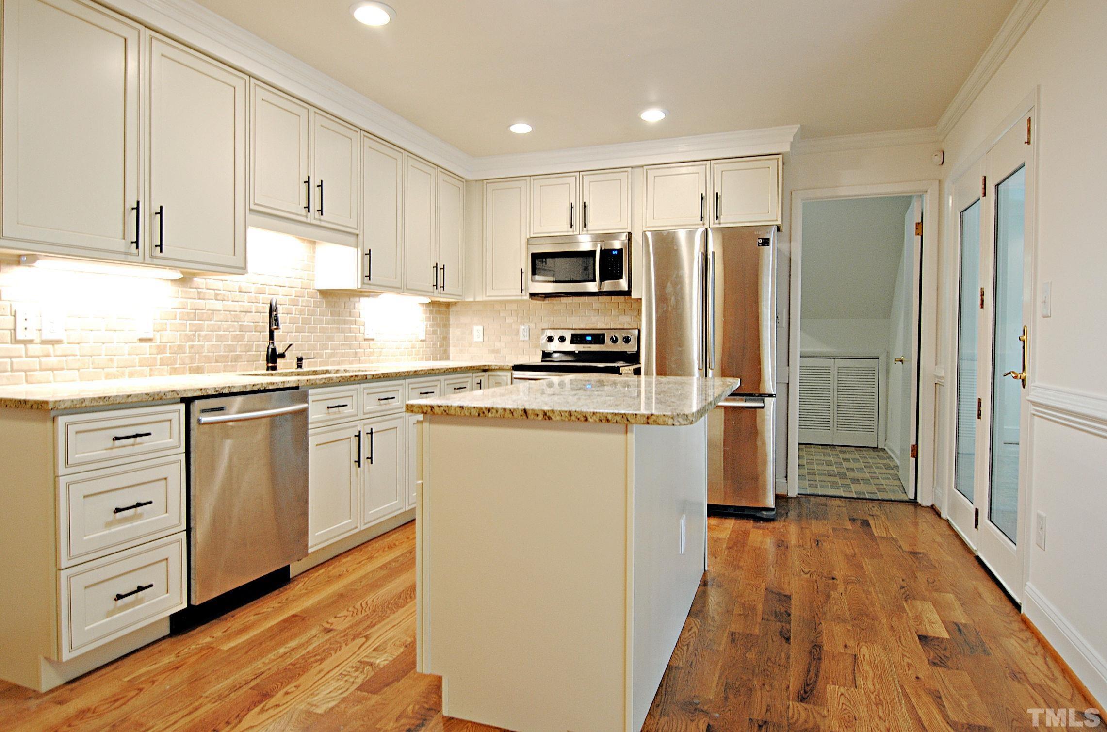 7106 Matthews Road Durham, NC 27712 - Photo 9 of 30 a kitchen with white cabinets and stainless steel appliances