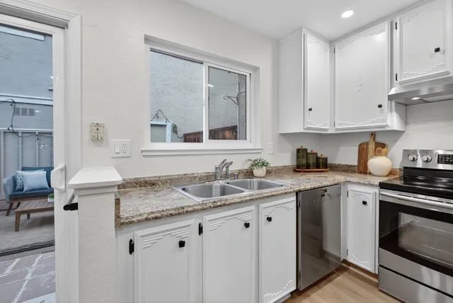a kitchen with granite countertop a sink stove and cabinets