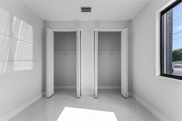 an empty room with windows and closet