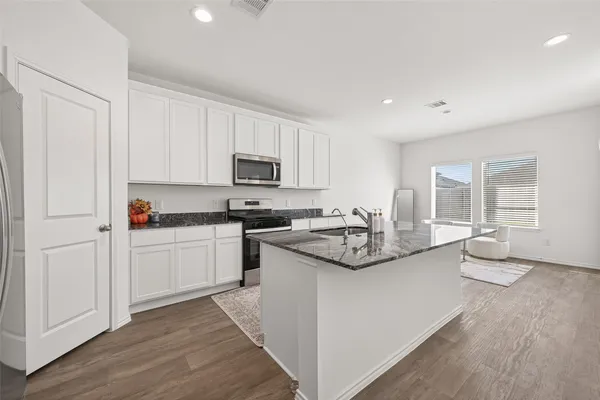 a kitchen with stainless steel appliances white cabinets a sink and a stove