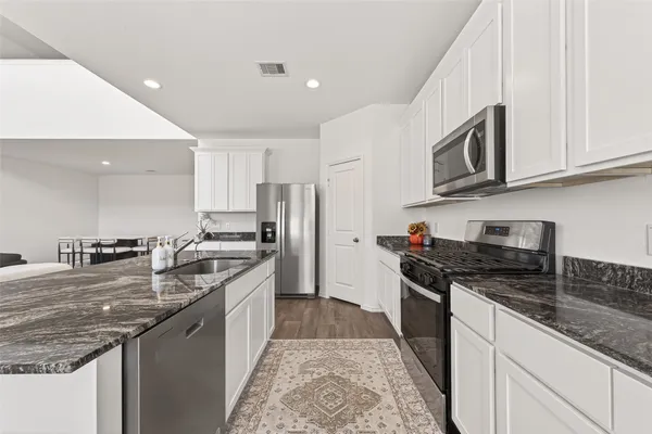a kitchen with stainless steel appliances granite countertop a stove a sink and a refrigerator