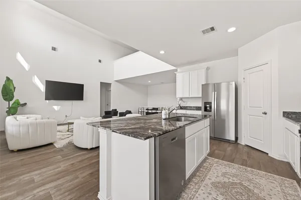 a kitchen with stainless steel appliances granite countertop a stove refrigerator and white cabinets with wooden floor