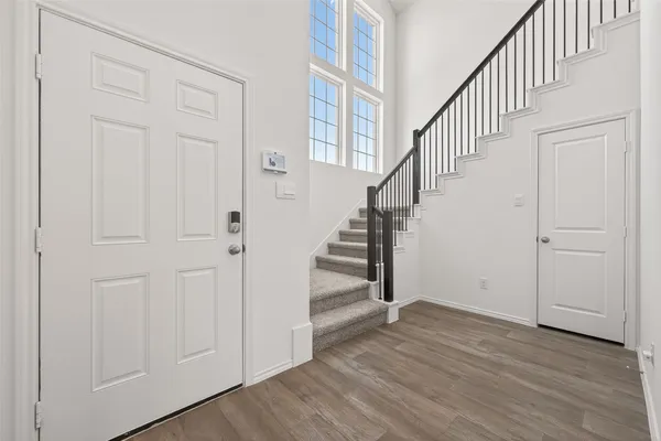 an entryway with hallway with wooden floor and staircase