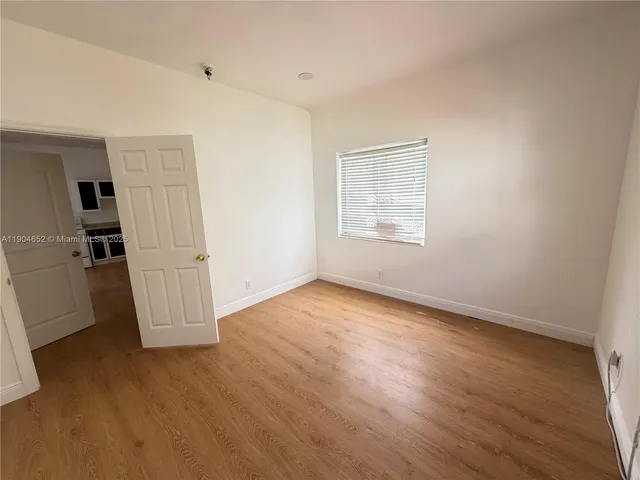 an empty room with wooden floor and window
