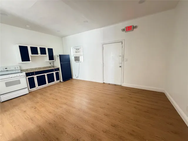 a view of a livingroom with wooden floor and kitchen