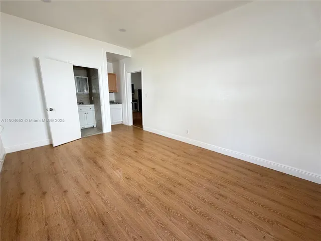 a view of an empty room with wooden floor and closet