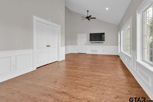 a view of an empty room with a window and a kitchen