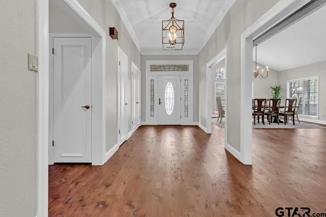 a view of a hallway with wooden floor and a chandelier
