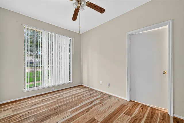 a view of empty room with wooden floor and fan