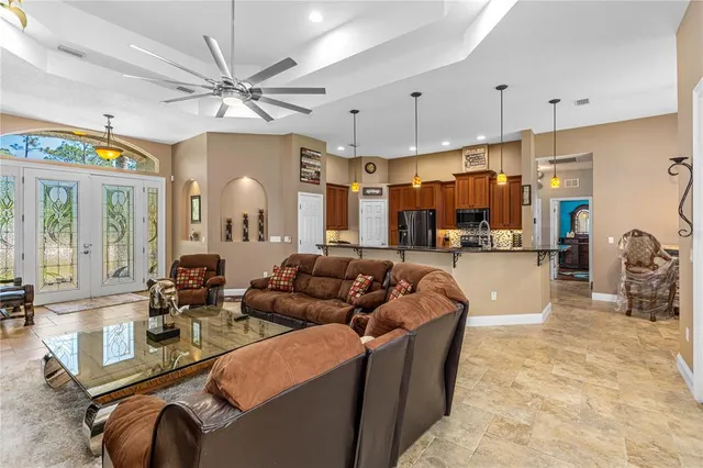 a living room with furniture a chandelier and kitchen view