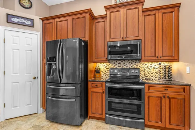 a kitchen with granite countertop a refrigerator stove and microwave