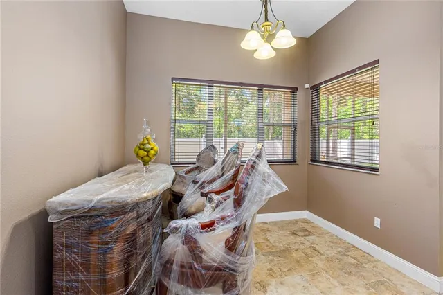a view of a dining room with furniture a chandelier and large windows