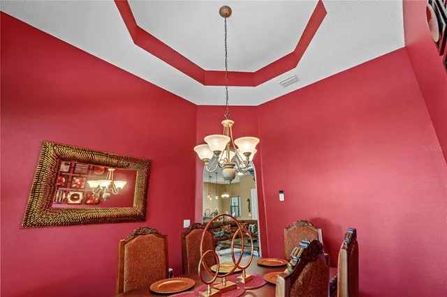 a spacious bedroom with a bed a chandelier and dresser