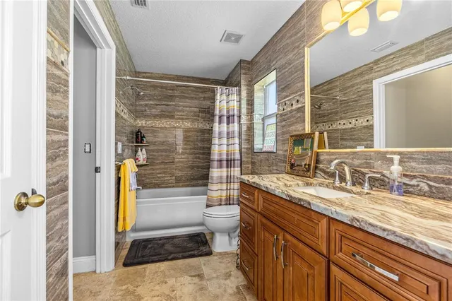 a bathroom with a granite countertop sink a toilet and a bathtub