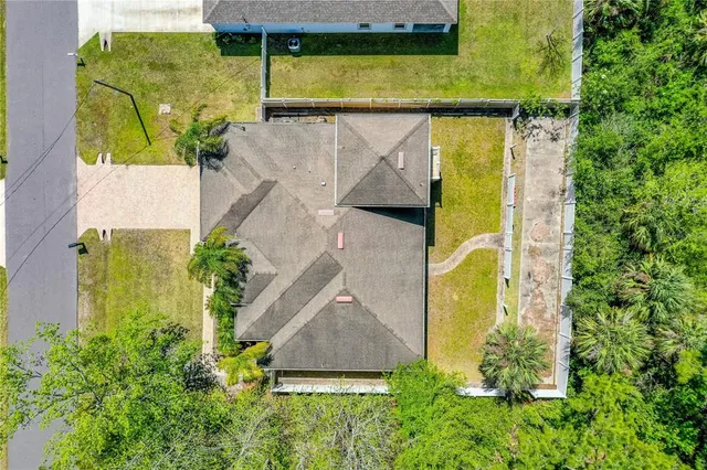an aerial view of a house with swimming pool and large trees
