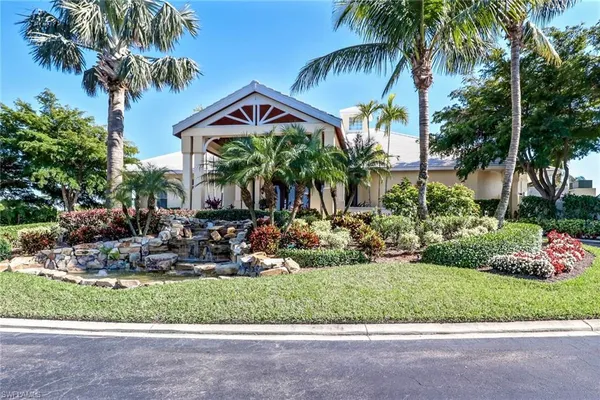 a front view of a house with a garden and palm trees