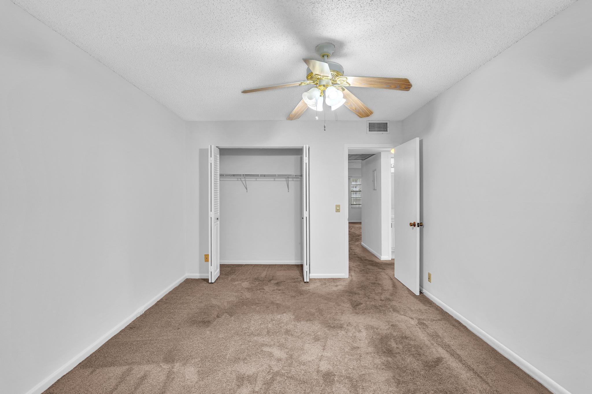 2066 Exeter Boca Raton, FL 33434 - Photo 21 of 60 an empty room with a chandelier fan and closet