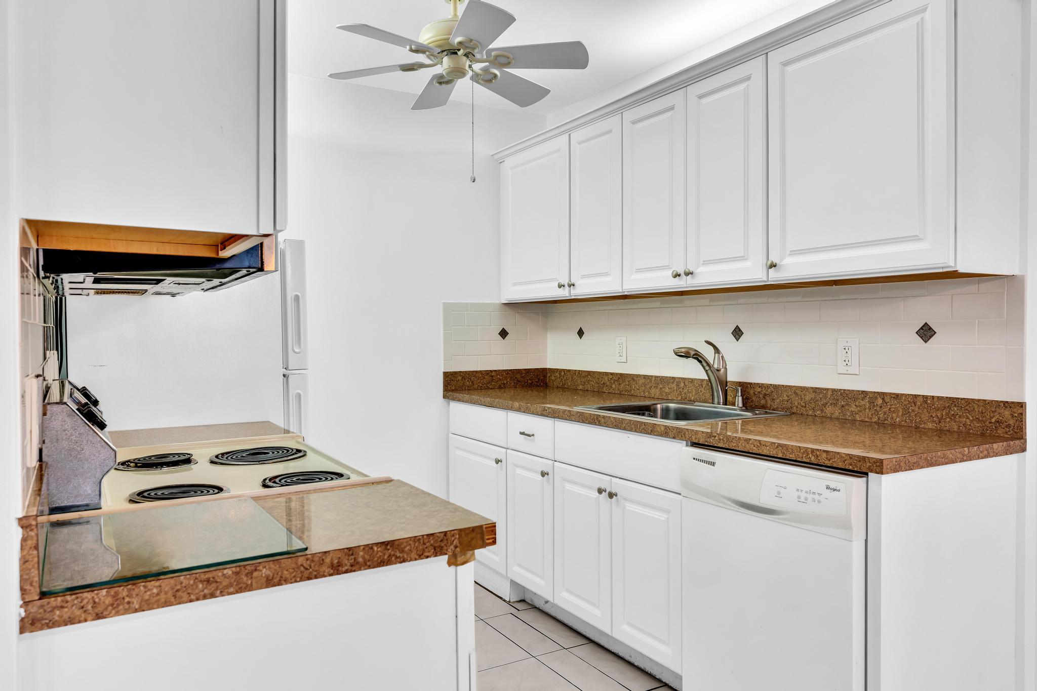 2066 Exeter Boca Raton, FL 33434 - Photo 10 of 60 a kitchen with granite countertop a sink stainless steel appliances and white cabinets