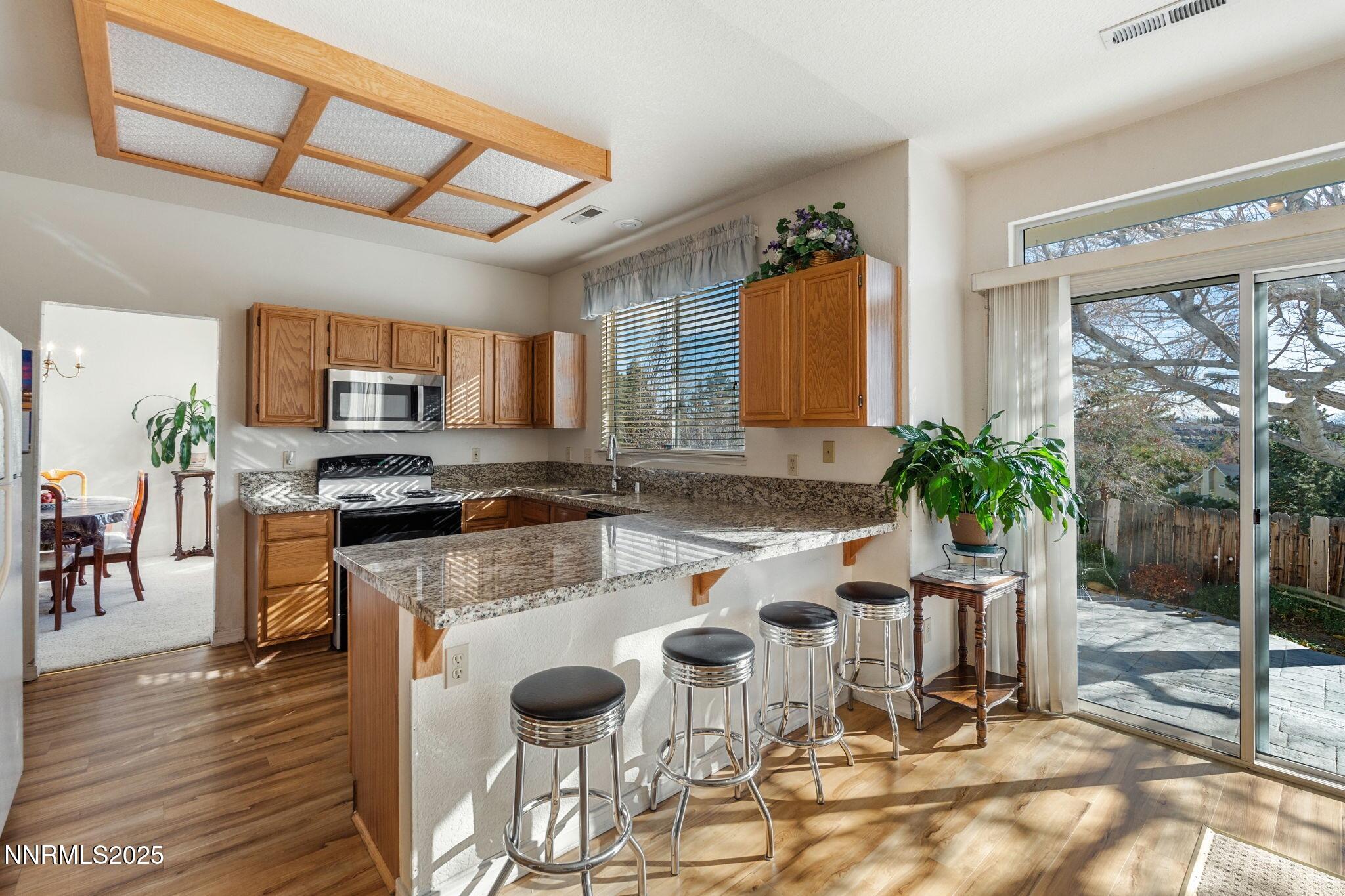 3952 Regal Drive Reno, NV 89503 - Photo 4 of 16 a kitchen with stainless steel appliances granite countertop a stove a sink a microwave refrigerator and chairs