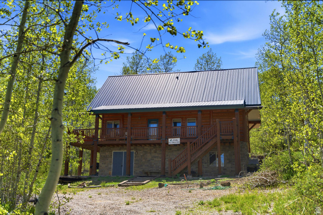 2096 South Aspen Ridge Coalville, UT 84017 - Photo 34 of 44 Log cabin exterior with a metal roof, featuring a stone foundation and an upper-level balcony