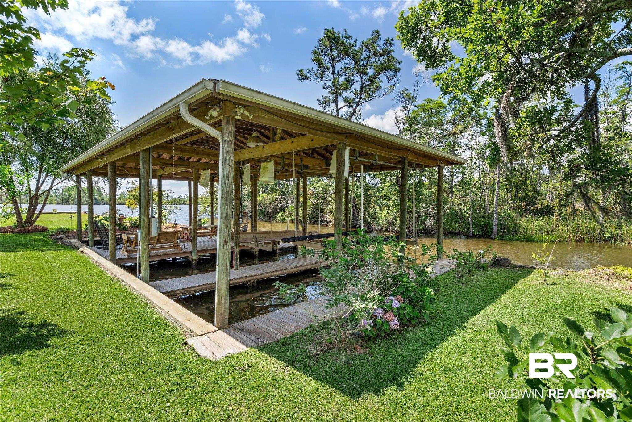 3801 Point Road Mobile, AL 36619 - Photo 37 of 55 Covered dock with a gabled roof, featuring multiple boat slips and a built-in seating area