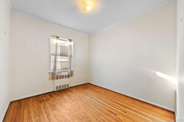 an empty room with wooden floor and windows with curtains