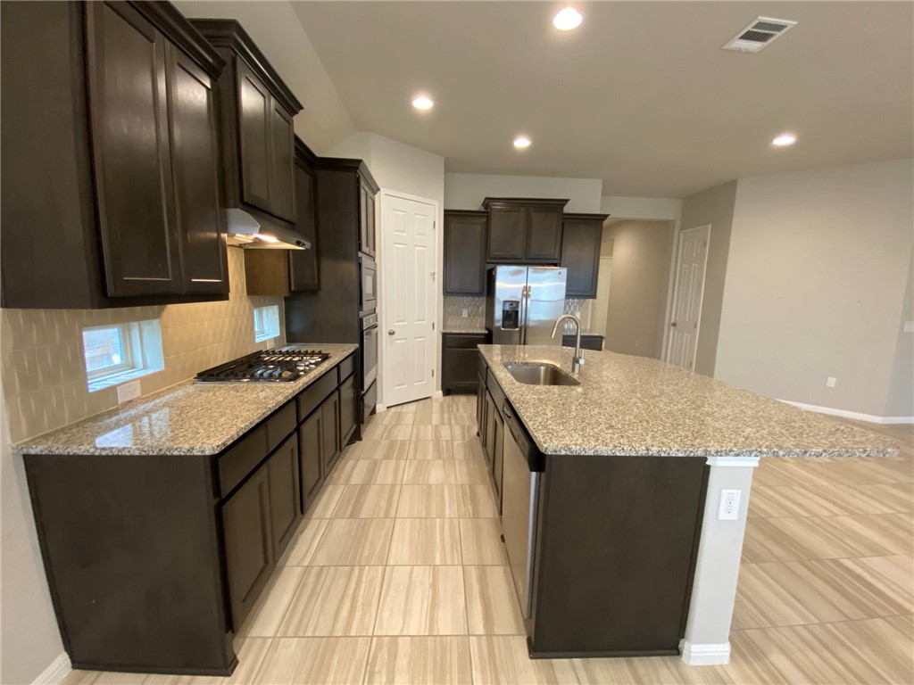 a kitchen with granite countertop stainless steel appliances and view living room
