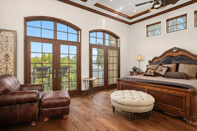 a bedroom with a bed a dresser and potted plants with wooden floor