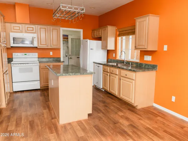 a view of a kitchen with kitchen island a counter top space appliances and a ceiling fan