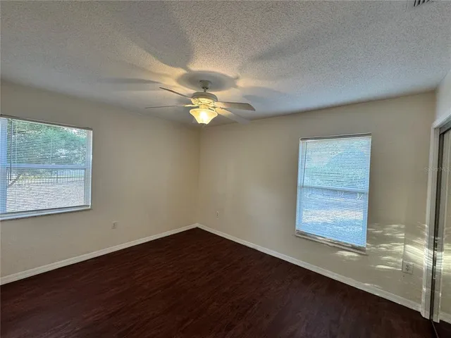 a view of an empty room with window and wooden floor