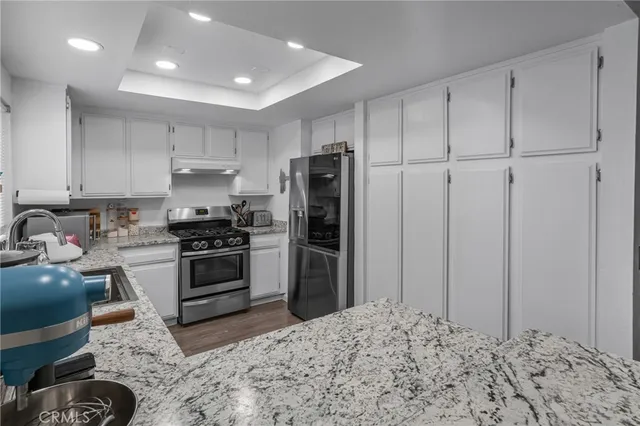 a kitchen with granite countertop white cabinets and white appliances