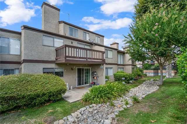 a view of a house with brick walls and a yard with plants