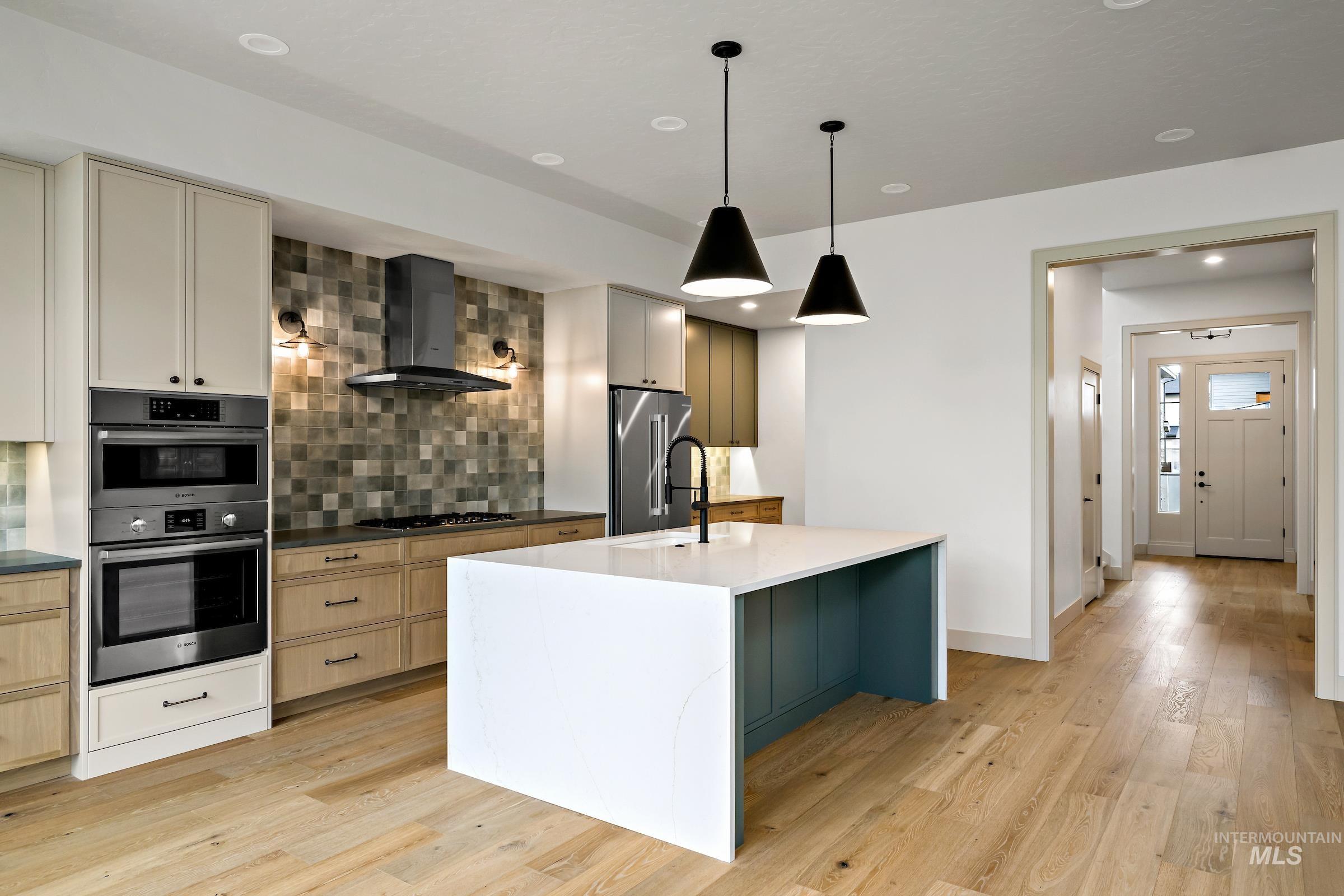 11696 North Rabbitbrush Way Boise, ID 83714 - Photo 12 of 32 Kitchen with decorative light fixtures, wall chimney range hood, appliances with stainless steel finishes, decorative backsplash, and dark stone countertops