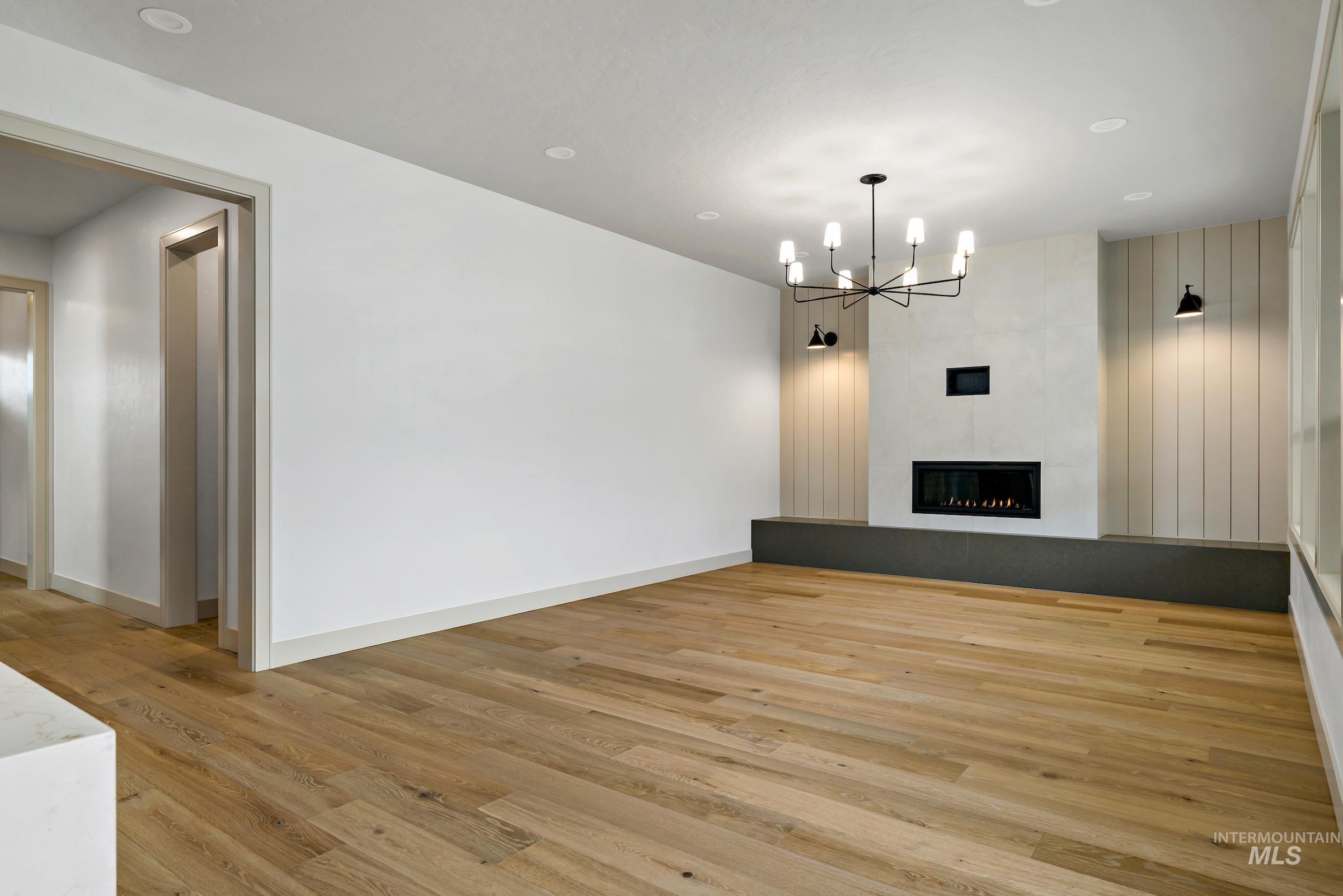11696 North Rabbitbrush Way Boise, ID 83714 - Photo 17 of 32 Unfurnished living room with light wood-style flooring, recessed lighting, a chandelier, and a fireplace