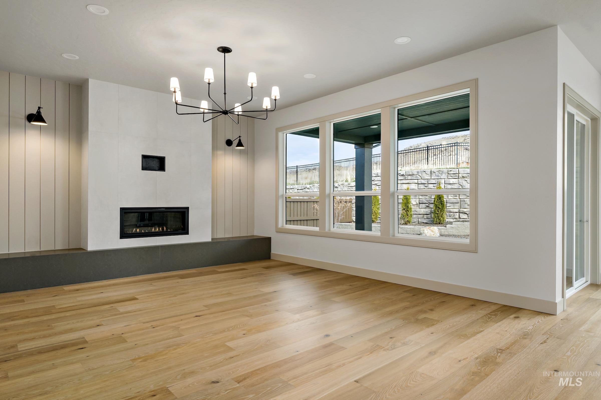11696 North Rabbitbrush Way Boise, ID 83714 - Photo 18 of 32 Unfurnished living room featuring light wood finished floors, a fireplace, and a chandelier