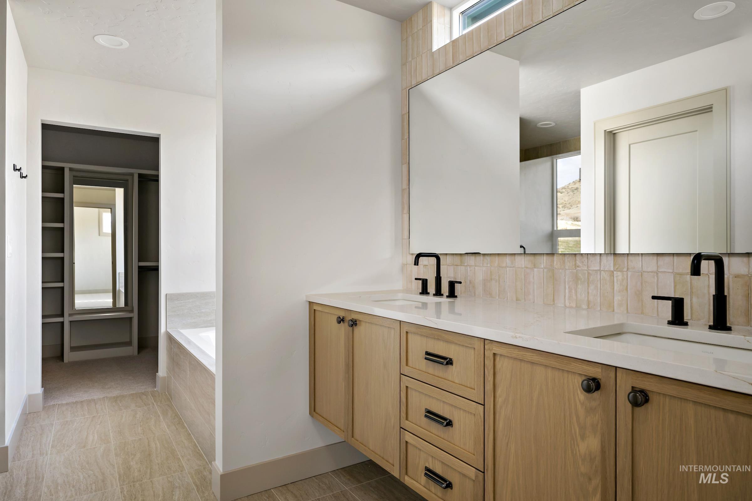 11696 North Rabbitbrush Way Boise, ID 83714 - Photo 24 of 32 Full bathroom featuring double vanity, a walk in closet, a garden tub, and tasteful backsplash