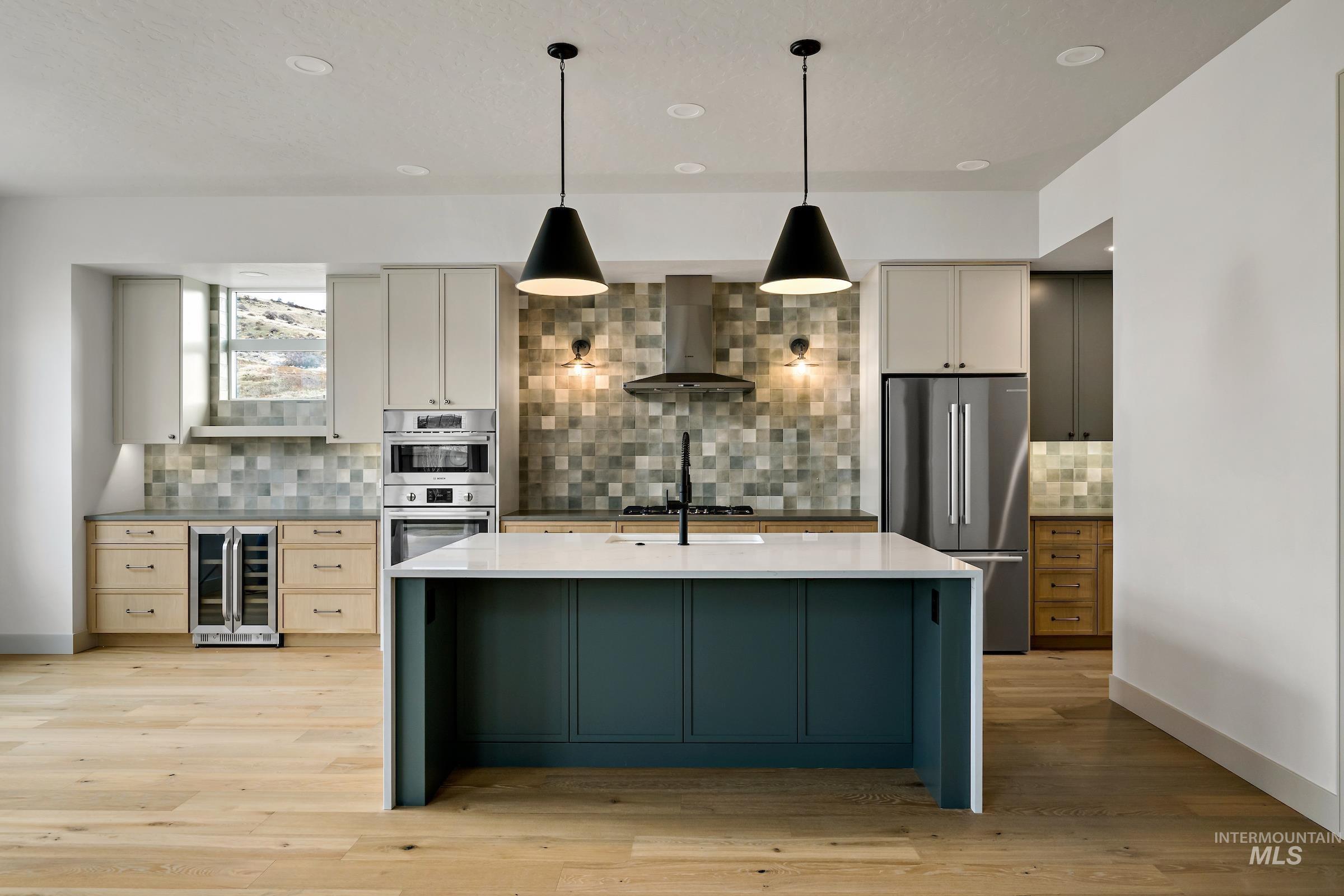11696 North Rabbitbrush Way Boise, ID 83714 - Photo 2 of 32 Kitchen with appliances with stainless steel finishes, decorative light fixtures, wine cooler, wall chimney range hood, and light stone counters